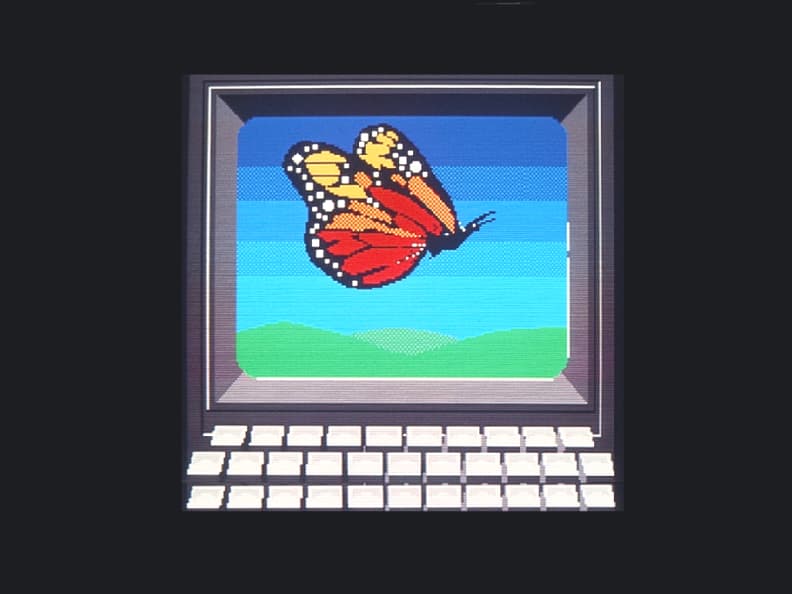 Une image dessinée à l’aide de Télidon représentant un écran d’ordinateur et un clavier. Un papillon se trouve sur l’écran de l’ordinateur.