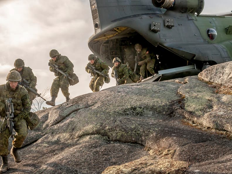 Des militaires canadiens, en ligne, débarquent de leur hélicoptère d’attaque. Munis de leurs armes et équipements de combat, ils sont déterminés, concentrés et prêts à affronter toutes les aventures qui les attendent sur un territoire étranger.