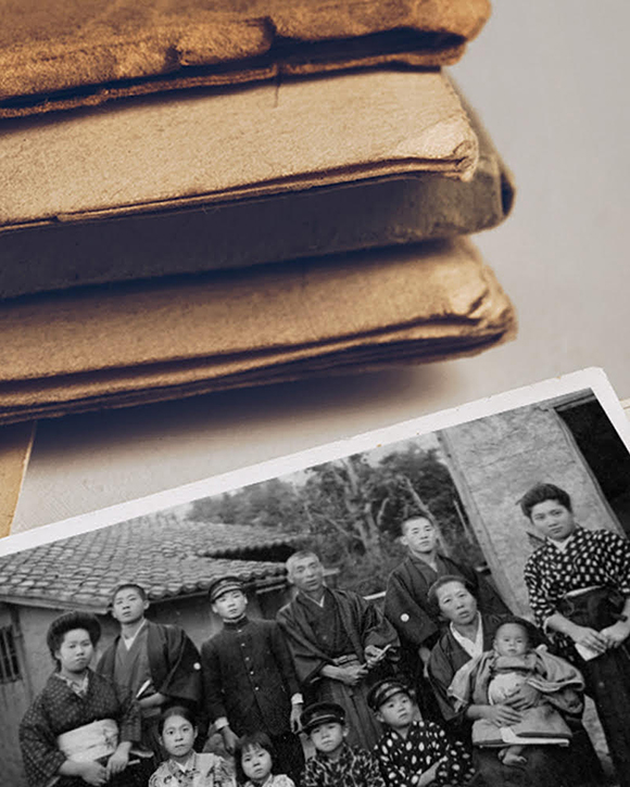 Un paquet de documents aux tons sépia sur un bureau avec un album aux tons sépia et une photo en noir et blanc de personnes
